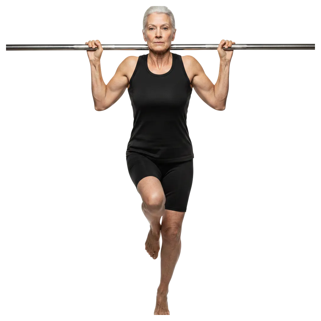 An elderly woman in a black athletic outfit grips a horizontal bar with both hands while balancing on one foot, her other leg hanging down freely. Her expression is focused, showcasing strength and po