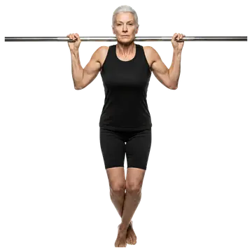 An elderly woman with short gray hair is performing a pull-up on a horizontal bar, showcasing strength and determination. She wears a tight-fitting black tank top and shorts, highlighting her athletic